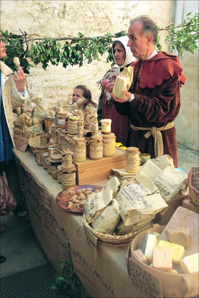 L'immagine è parte della ricca raccolta fotografica “Puglia per tutte le Stagioni” vol. 2, prodotta dall'Assessorato al Turismo e Industria Alberghiera della Regione Puglia per raccontare la Puglia attraverso immagini suddivise in 5 settori principali: Città e Paesi, Settimana Santa, Territorio, Feste – Sagre – Tradizioni, Mercati – Prodotti – Cucina. L'immagine in oggetto ritrae un uomo vestito a tema medievale, durante una festa popolare di Bitetto, nell'atto di vendere alcuni prodotti gastronomici e artigianali tipici del luogo. Il corteo storico rievoca un epico incontro dal passato, a metà tra il leggendario e lo storico, tra il Frate Giacomo e il duca Andrea Matteo Acquaviva. Secondo la tradizione infatti, nell'anno 1485 quest'ultimo aveva partecipato alla Congiur...