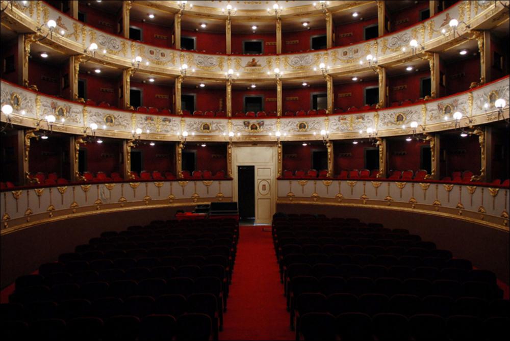 L'immagine è parte della campagna fotografica realizzata dalla fotografa Margherita Mirabella per Teatro Pubblico Pugliese, che con i suoi scatti ha ripreso le eleganti architetture e i rifiniti dettagli di alcuni dei più bei teatri pugliesi e di alcuni spettacoli teatrali portati in scena in questi ultimi anni. La panoramica immortala l'interno di Teatro Curci di Barletta, importante contenitore culturale cittadino intitolato al compositore Giuseppe Curci situato in pieno centro. L'aspetto attuale è quello del nuovo teatro, costruito interamente sul precedente e più antico teatro di San Ferdinando, per volontà del comune, che lo acquistò ordinandone l'abbattimento dopo il suo crollo parziale. I lavori iniziarono nel 1868 con la direzione dell'architetto Federico Santac...