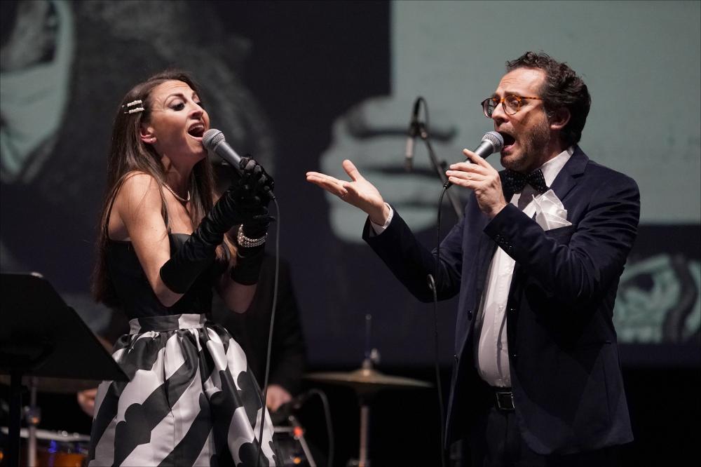 <div>Lo scatto cattura un momento dello spettacolo musicale <em>I giorni dello swing</em>, ideato e interpretato da Alfredo De Giovanni insieme a Floriana Ferrante, Domenico Lopez, Marco Boccia e Antonio Ninni. Andato in scena il 27 gennaio 2024 al Teatro Sebastiano Arturo Luciani di Acquaviva delle Fonti (Ba), lo spettacolo accompagna il pubblico in un viaggio nella storia dello swing italiano.</div><div>Il racconto si muove tra le due guerre mondiali, in un’Italia in cui lo swing – con le sue sonorità nuove e vitali – veniva osteggiato dal regime fascista e definito sprezzantemente “antimusica negra”. Eppure, proprio in quel clima di censura e diffidenza, artisti come Natalino Otto, il Trio Lescano, Gorni Kramer e, più tardi, Fr...