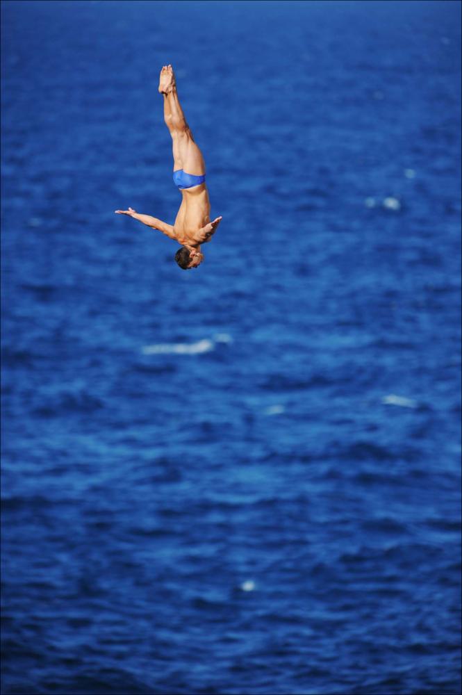 L'immagine digitale è una fotografia scattata nell'agosto del 2010 con luce pomeridiana dal fotografo Sergio Scagliola durante il Red Bull Cliff Diving World Series, l'ormai nota competizione internazionale di tuffi estremi da grandi altezze più famosa al mondo, creata nel 2009 dalla nota azienda di bibite, che si svolge in tutto il mondo. Adrenalina e sangue freddo contraddistinguono questa competizione, unica al mondo, nella quale tuffatori provenienti da tutte le nazioni gareggiano in scenari naturali mozzafiato che permettano agli sportivi di tuffarsi da un'altezza minima di 26 metri sul livello del mare. Dal 2008, la Red Bull Cliff Diving fa tappa anche nella suggestiva ambientazione naturale di Polignano a Mare, cittadina dal caratteristico nucleo storico abitativ...