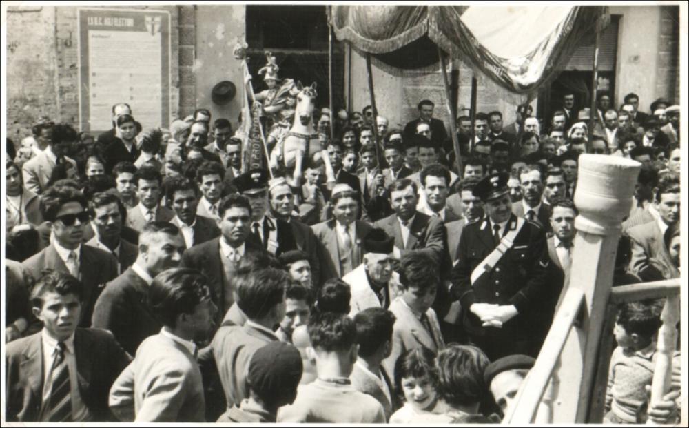 <div><strong>Foto storica (probabilmente anni ’50):</strong> il parroco, in primo piano, è circondato da una folla mentre si dirige verso la cassa armonica per pronunciare il suo discorso, ricordando alla comunità l’esempio di fede e di amore del Santo Patrono. In fondo, vediamo la statua di San Giorgio, portata in processione. </div><div><br></div><div>La Festa Patronale di San Giorgio Martire si celebra annualmente il 22 e il 23 aprile a Chieuti, in provincia di Foggia. Questa ricorrenza non è solo un momento di devozione religiosa, ma rappresenta un'espressione autentica del legame storico, culturale e sociale tra la comunità di Chieuti e il proprio Patrono. San Giorgio, venerato come cavaliere e martire, simboleggia coraggio, fede e p...