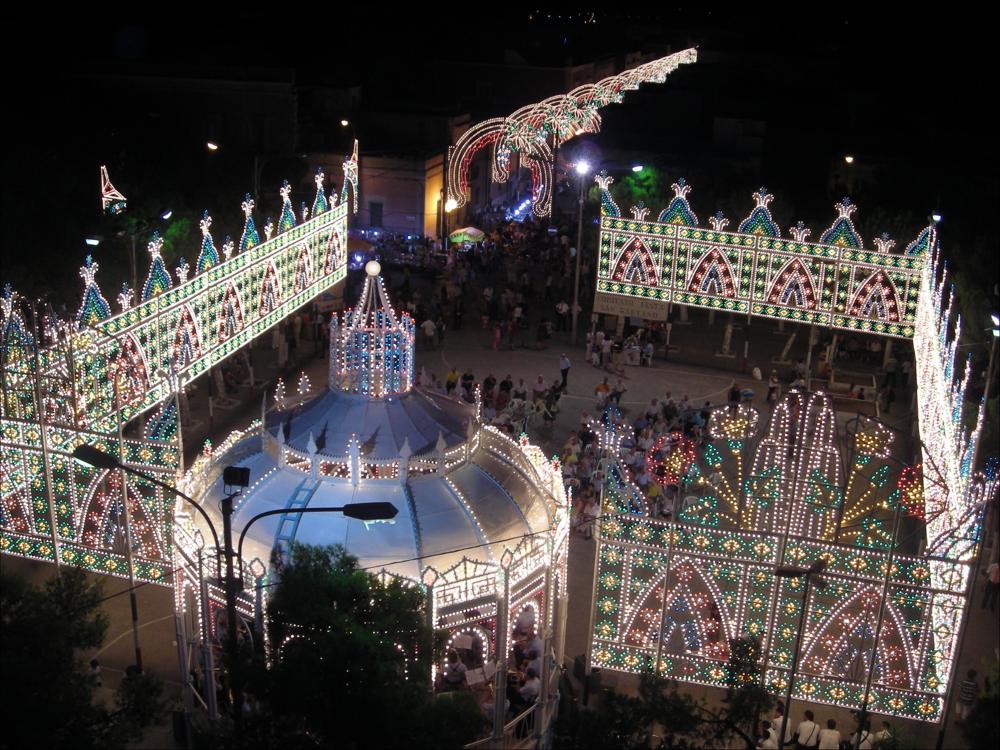 <div class="ql-editor"><div>Lo scatto fotografico immortala l’atmosfera di festa delle luminarie colorate che abbelliscono le strade cittadine e la piazza di Lizzano (TA) con la suggestiva Cassarmonica che ospita il gruppo bandistico del paese, pronto ad allietare il pubblico dei fedeli con musica e canti in onore del Santo Patrono Gaetano.</div><div>La festa patronale in onore di San Gaetano da Thiene si celebra a Lizzano il 6 e 7 agosto, con solenni festeggiamenti religiosi e civili.</div><div>Le celebrazioni iniziano nella Chiesa Matrice di San Nicola con la Novena, che si svolge dal 29 luglio al 6 agosto. In questo periodo viene solennemente esposta l’antica statua del Santo, secondo il tradizionale rito dell’intronizzazione. Ogni sera si recita la...