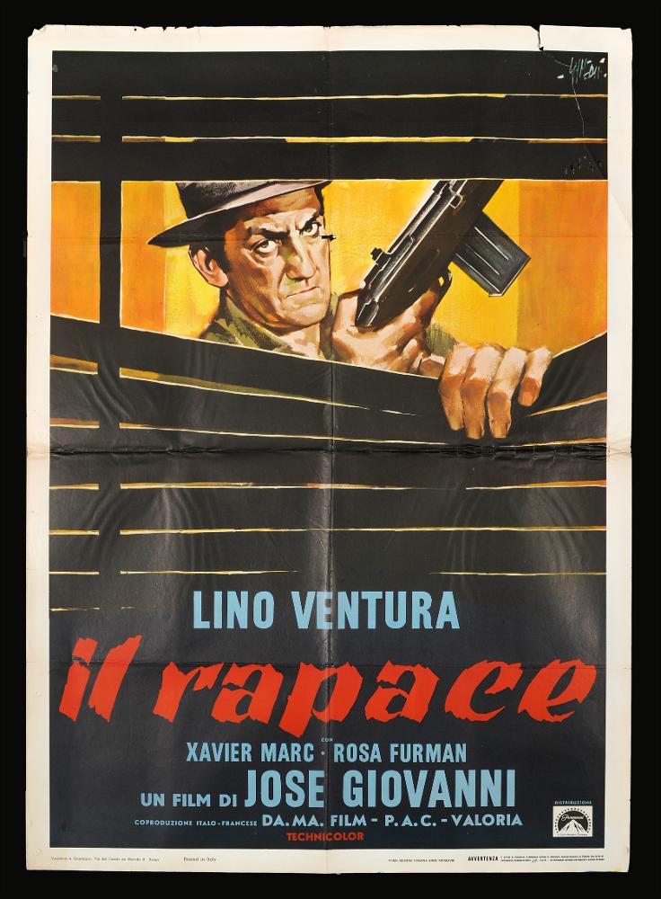L'immagine riproduce uno dei manifesti conservati presso la Mediateca Regionale Pugliese (vedi Note). Si tratta di una delle versioni grafiche per il manifesto del film “Il rapace” del 1968 per la regia di José Giovanni, a firma dell'illustratore Sandro Symeoni come si legge in alto a destra. Pittore ferrarese tra i più prolifici disegnatori di cinema, Symeoni utilizzò un linguaggio non piano, ma dalle molteplici sfaccettature, mutevoli negli anni. In questo manifesto la composizione grafica è molto semplice, vi è la solo presenza del ritratto del protagonista Lino Ventura che sembra abbassare delle doghe di legno e in mano impugna un fucile. Il colore predominante è il nero ma, lo sfondo del giallo che sfuma verso i toni dell’arancio rendono l'atmosfera calda. Colpisce...
