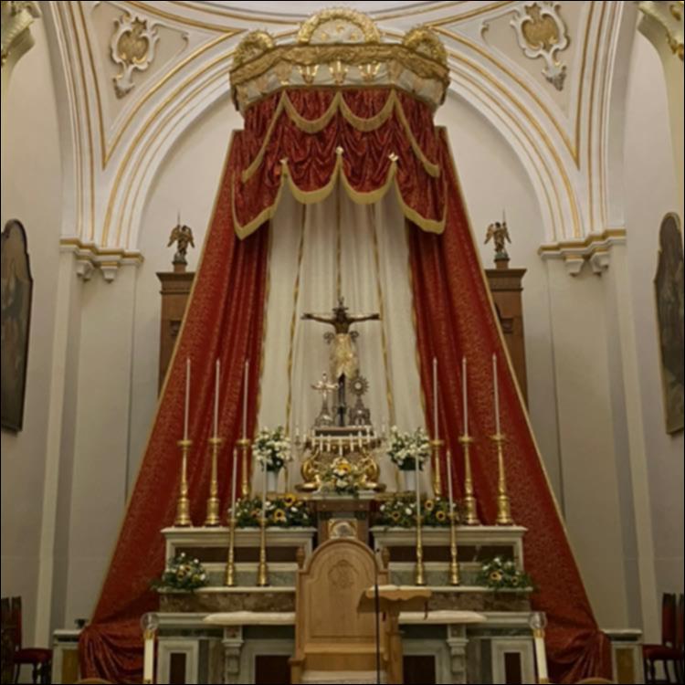 <div class="ql-editor"><div> Fotografia dell’altare della Chiesa del Santissimo Crocifisso di Latiano, dove è custodito il venerato Crocifisso ligneo scuro, noto come <em>Crocifisso Nero</em>, fulcro della devozione cittadina sin dal XVI secolo. L’immagine sacra raffigura Cristo morto sulla croce, con il costato trafitto, ed è oggetto di profonda venerazione da parte della comunità locale. Secondo la tradizione, il crocifisso giunse a Latiano grazie a una carovana di viandanti che, fermatasi lungo l’antica via Appia, lo lasciò alla popolazione dando origine al culto. L’altare, impreziosito nel tempo da interventi artistici e decorativi, custodisce la statua all’interno di una struttura lignea intagliata realizzata nel 16...