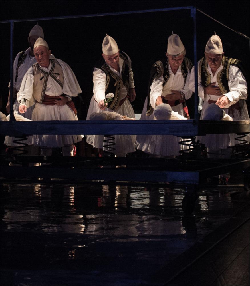 La fotografia in oggetto, ad opera di Tea Primiterra, immortala un momento dello spettacolo “Katër i Radës. Il Naufragio”, produzione nata dalla co-produzione della Biennale di Venezia e Koreja, messa in scena per la prima assoluta, il 12 ottobre 2014, nell'ambito del 58° Festival Internazionale di Musica Contemporanea della Biennale di Venezia. Lo spettacolo, per la regia di Salvatore Tramacere, è il risultato dell'unione del libretto di Alessandro Leogrande, tratto dal suo romanzo-reportage “Il naufragio” (Feltrinelli, 2011) e le musiche del compositore albanese Admir Shkurtaj, per mettere in scena una delle tragedie dell'emigrazione, lo speronamento da parte della corvette Sibilla della Marina Militare Italiana e l'affondamento dell'imbarcazione albanese Katër i Radë...