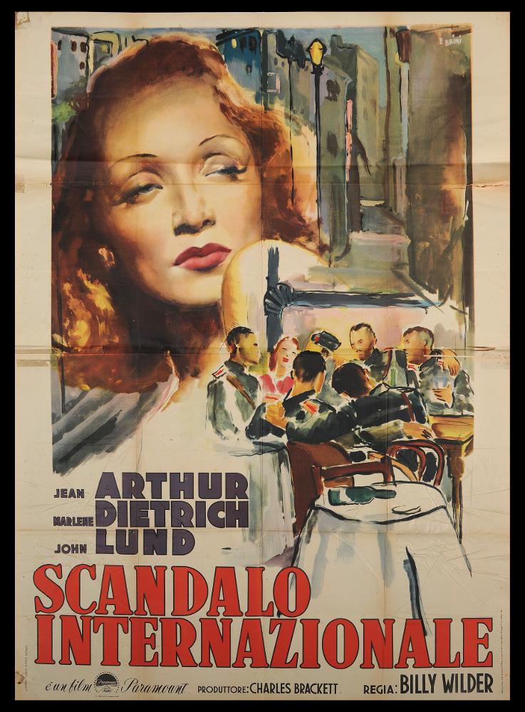 L'immagine riproduce uno dei manifesti conservati presso la Mediateca Regionale Pugliese (vedi Note). Si tratta del manifesto del film italiano "Scandalo internazionale", la cui illustrazione è a firma di Ercole Brini. È una composizione pittorica delicata, caratteristica che contraddistingue tutte le sue opere; Brini infatti prediligeva l'uso degli acquerelli, tecnica che gli permetteva di creare racconti in cui le figure si fondono al paesaggio, figure diverse si fondono una nell'altra, in atmosfere impalpabili e ricche di fascino. Anche questa è ricca di narrazione e poesia: il ritratto magnifico di Marlene Dietrich occupa gran parte dello spazio grafico, attirando l'attenzione del fruitore. Lo sfondo urbano e la scena di gruppo completano l'insieme rendendo l'atmosf...
