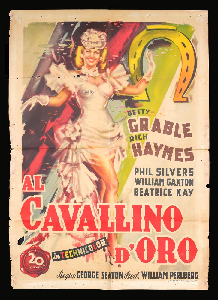 “Il cavallino d’oro” (titolo originale “Diamond Horseshoe”) è un film di genere commedia del 1945, diretto da George Seaton, con Betty Grable e Dick Haymes.
Il manifesto cinematografico non presenta firma dell'autore.
La composizione è estremamente dinamica, i colori vivaci rendono l’atmosfera briosa. La showgirl protagonista, ritratta a figura intera, sfoggia un abito di scena che enfatizza la sua sfolgorante bellezza. Un grande ferro di cavallo dorato campeggia simbolicamente sulla destra dell'immagine.   In basso vediamo il titolo del film, a grandi lettere di un rosso vivo.
Il manifesto originale è conservato nell’Archivio della Mediateca Regionale Pugliese....