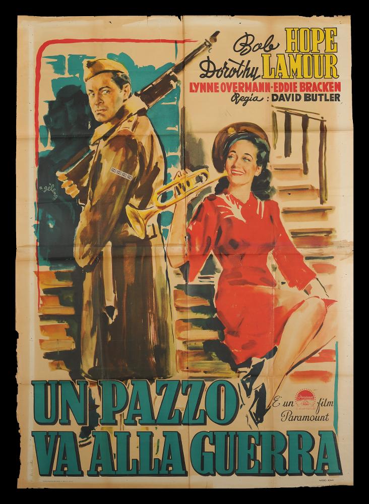 L'immagine riproduce uno dei manifesti conservati presso la Mediateca Regionale Pugliese (vedi Note). Si tratta di uno dei manifesti del film “Un pazzo va alla guerra” del 1941 per la regia di David Butler. La firma che leggiamo sul lato sinistro appartiene all’illustratore romano Rinaldo Gèleng che firma anche l'altro manifesto presente in collezione. Classe 1920 fu artista poliedrico ed eclettico, dopo gli studi d'arte, visse e lavorò per molti anni a Parigi, poi a Milano dove realizzò una serie di copertine per Mondadori e infine a Roma, dove creò alcuni manifesti per i film di Fellini. Il suo stile fresco e pittorico è fatto di pennellate liquide e sfumate, con spunti grafici originali, composizioni personali, in cui rivela la sua dote di ritrattista come si può not...