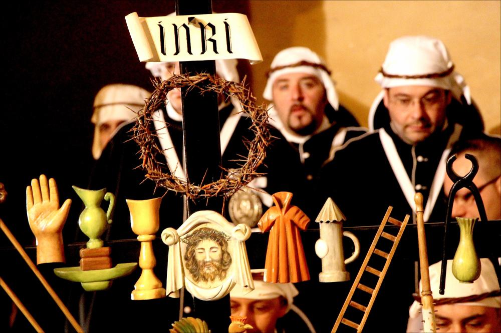 L'immagine digitale è scattata a luce ambiente durante uno dei momenti caratteristici dei riti della lunga Settimana Santa che nel periodo pasquale invade la città di Taranto di sacralità, tradizione e storia. La Settimana Santa, considerato tra gli eventi più importanti dell'anno a Taranto e in tutta la Puglia, inizia generalmente con la Domenica delle Palme, giornata nella quale si ricorda l'ingresso a Gerusalemme di Gesù Cristo salutato dal popolo con dei rametti di ulivo, simbolo di pace. I riti entrano nel vivo dell'atmosfera sacra dal giovedì Santo, giorno nel quale tutta la cittadinanza, profondamente coinvolta, rivive i momenti intensi della Passione di Cristo e dei dolori della Vergine Addolorata. Lo scatto cattura un dettaglio della processione dei Perdoni che...