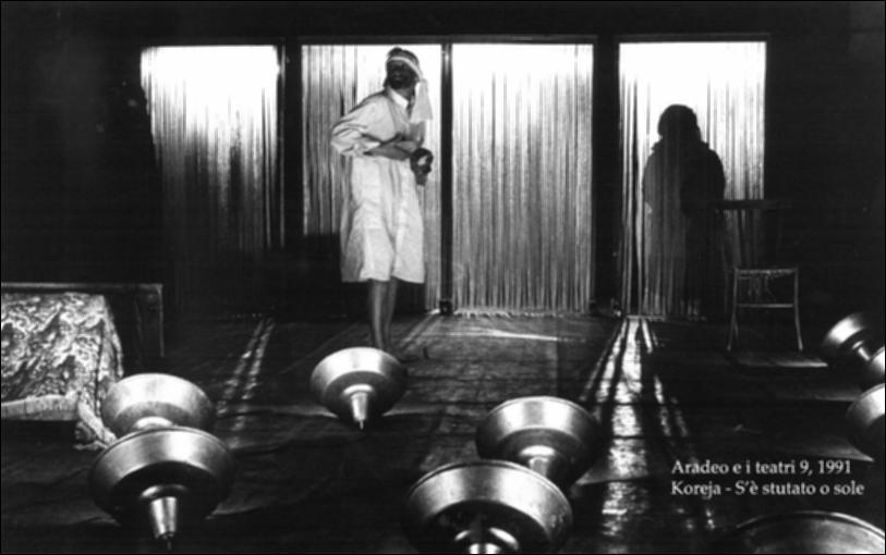 La fotografia in bianco e nero cattura un momento dello spettacolo "S'è stutato o' sole" messo in scena nel 1991 dalla compagnia Koreja, nata nel 1983 nel piccolo borgo salentino di Aradeo, dove ha dato vita anche al prestigioso festival annuale "Aradeo e i Teatri", avviato nell'anno della loro fondazione. La pièce, diretta dal regista del gruppo Salvatore Tramacere, racconta di un Sud nel quale viene emanato un editto che vieta alle donne di avere figli. Da qui, nasce il tragicomico percorso di una madre, suddiviso in quattro movimenti che rappresentano quattro diversi stati d'animo, all'inseguimento di un figlio, insieme ad un'altra donna, non madre. Con lo spettacolo, Koreja dà vita ad una "farsa tragica" nella quale le donne affrontano situazioni vere e crude e i fa...