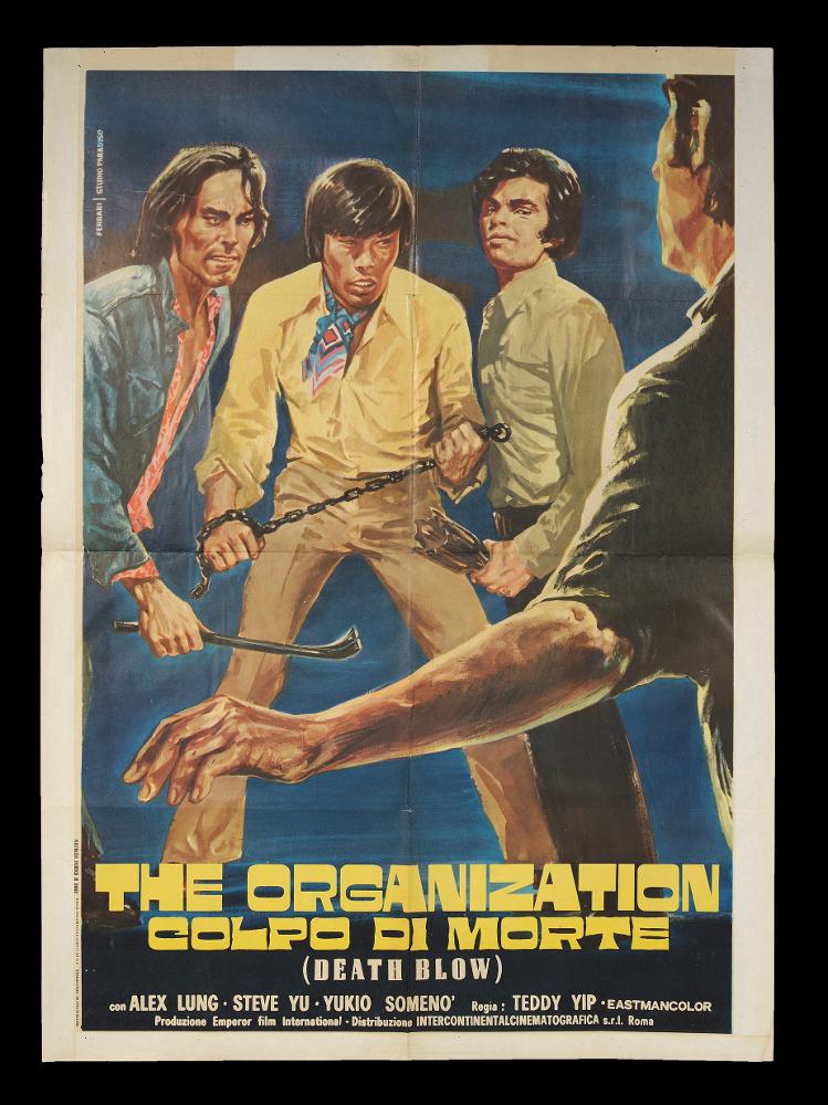 L'immagine riproduce uno dei manifesti conservati presso la Mediateca Regionale Pugliese (vedi Note). Si tratta della versione grafica del manifesto del film "The Organization - Colpo di morte". L’illustratore Mario Ferrari firma la composizione in oggetto con lo Studio Paradiso. Il fondo è blu scuro e uniforme e questo permette di esaltare i personaggi a figura intera rappresentati e di farci quasi entrare nella scena, immedesimandoci nell'uomo di spalle, che deve affrontare la lotta con il gruppo delle Tigri Rosse. Questo tipo di grafica è tipica degli anni '60-'70 e si ritrova spesso nelle composizione dei film di produzione orientale in cui compaiono riferimenti alle arti marziali. La pittura si mostra tradizionale, realistica e ricca di dettagli che rendono la dina...