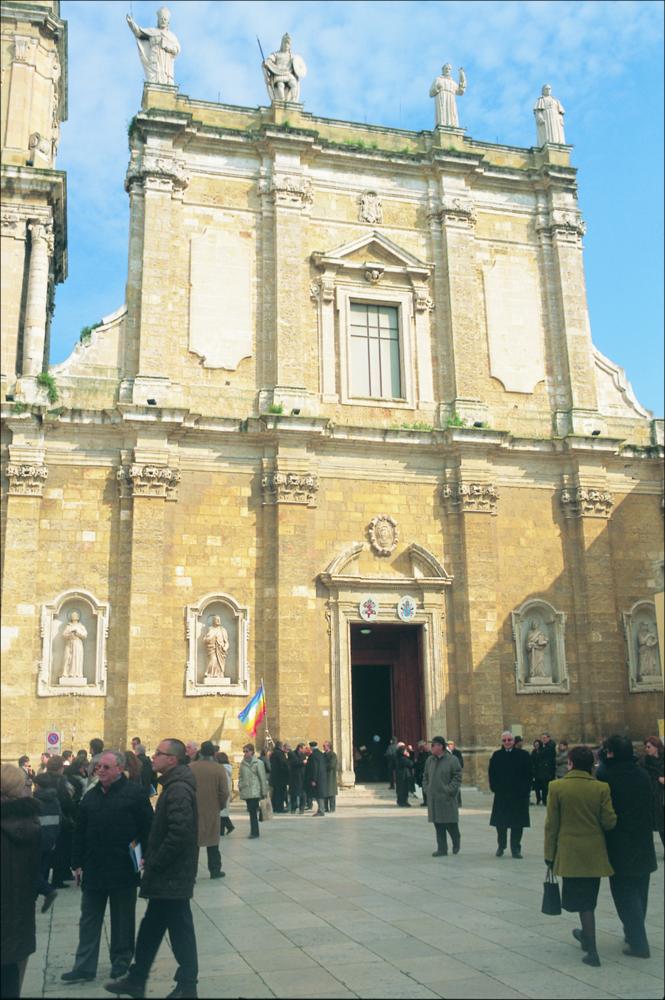 La fotografia è parte della ricca raccolta fotografica “Puglia per tutte le Stagioni” vol. 2, prodotta dall'Assessorato al Turismo e Industria Alberghiera della Regione Puglia, per raccontare la Puglia attraverso immagini suddivise in 5 settori principali: Città e Paesi, Settimana Santa, Territorio, Feste – Sagre – Tradizioni, Mercati – Prodotti – Cucina. L'immagine cattura la facciata della Cattedrale di Brindisi, architettura sacra che domina imponente in Piazza Duomo. Intitolata a San Giovanni Battista oggi è il risultato della sua ricostruzione, avvenuta dopo che fu quasi completamente distrutta da un terremoto nel 1746. L'attuale edificio barocco con annesso campanile ricalca però l'originaria pianta romanica, che presentava un impianto basilicale senza transetto, ...