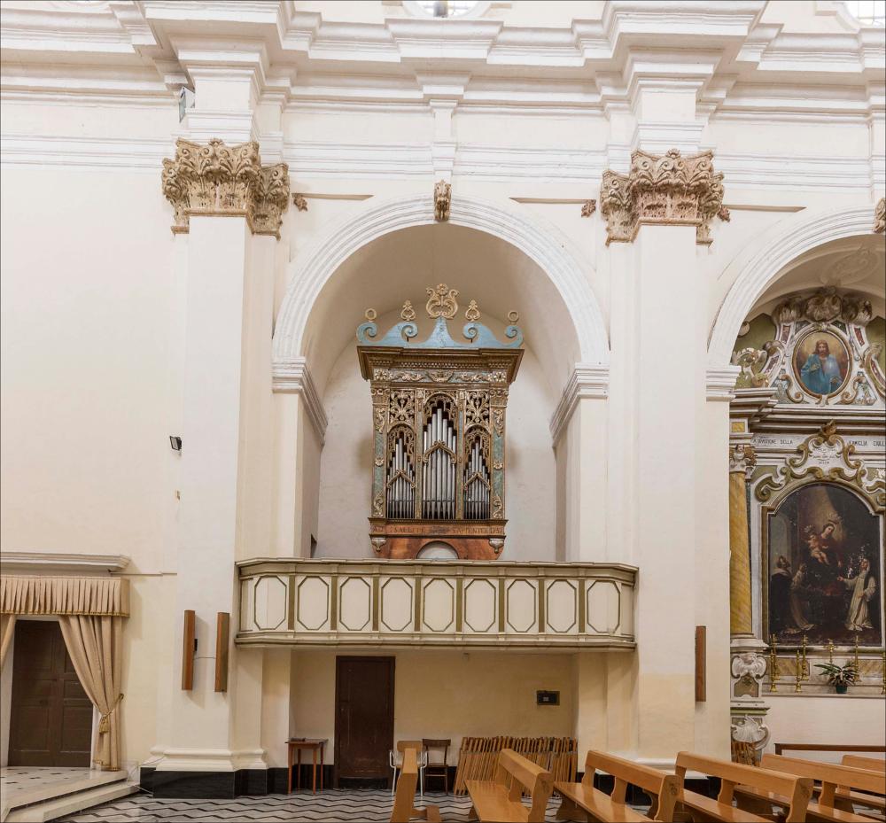 L’immagine digitale raffigura l’organo nella sua collocazione all'interno della chiesa di S. Michele Arcangelo a Castrignano del Capo, in provincia di Lecce. La chiesa distrutta da un violento terremoto fu ricostruita nel 1743 e riaperta al culto nel 1753. Il portale centrale, sormontato da una piccola statua di San Michele (1619), rappresenta ciò che rimane dell’edificio precedente; fino al Novecento si conservavano anche le due torri in facciata a pianta quadrata del 1557 che fiancheggiavano l’edificio. All’interno si conservano pregevoli tele tra cui quelle dedicate a Sant’Oronzo, San Michele e San Giovanni e una scultura di San Michele del famoso scultore napoletano Nicola Fumo e tra gli arredi lignei si segnalano i confessionali settecenteschi e l’organo a canne. C...