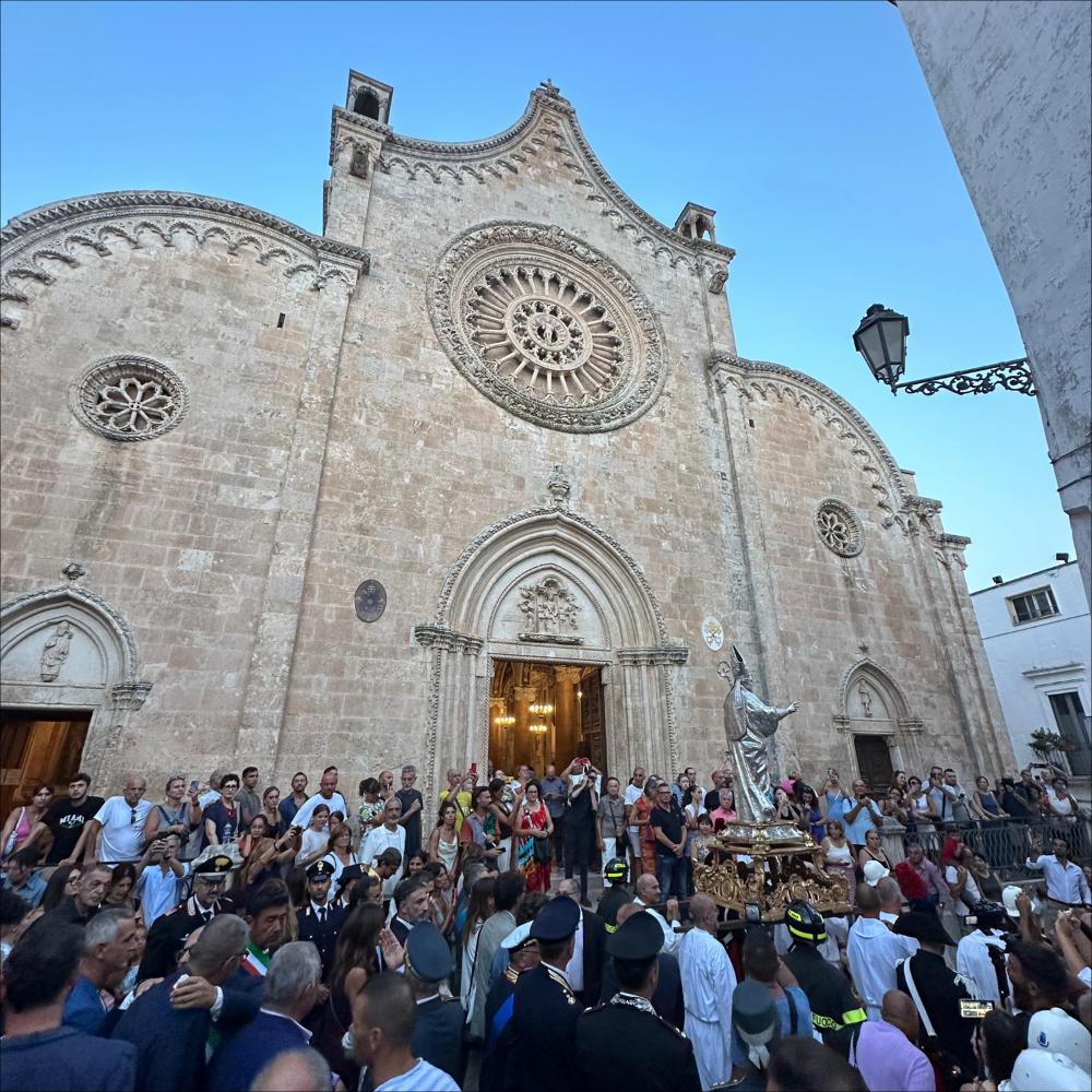 <div class="ql-editor"><div>In questa immagine il simulacro argenteo di Sant'Oronzo varca il portale della Concattedrale di Ostuni e dà inizio al solenne cammino processionale. È un momento carico di emozione: il Santo, custodito durante l’anno nel luogo sacro, esce tra il suono festoso delle campane e l’attesa della folla, segnando l’avvio dei festeggiamenti patronali.</div><div><br></div><div>A Ostuni, ogni anno dal 25 al 27 agosto, si rinnova uno degli appuntamenti più sentiti dalla comunità: la Cavalcata in onore di Sant'Oronzo, solenne processione equestre che unisce fede, tradizione e identità cittadina. Attualmente la processione e la Cavalcata sono rese possibili grazie alla sinergia tra la Parrocchia Concattedrale di O...