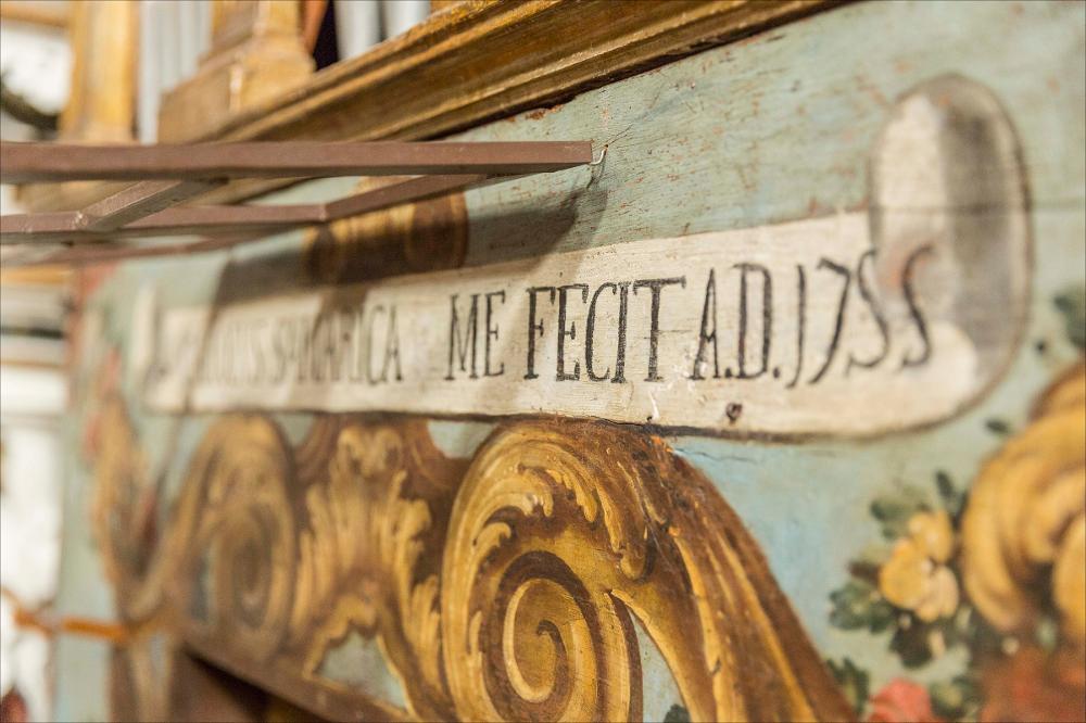 L'immagine cattura un dettaglio dell’organo in oggetto, collocato nella collegiata di S. Nicola (o Chiesa della Presentazione del Signore) a Maglie. La collegiata si fa risalire ai primi anni del secolo XVI quando ancora si praticava il rito greco; nel 1681 è già attestato il rito latino e, a seguito dello stato del degrado dell’edificio e di un terremoto del 1743, fu completamente demolita e ricostruita nel 1765. I lavori di costruzione sono attribuiti al mastro muratore Giuseppe Serio con la collaborazione delle maestranze salentine, i Morgese e i Fasano. Successivo è stato l’intervento del capomastro Giuseppe Negro di Parabita e dell’architetto Felice De Palma di Alessano, al quale si assegna il disegno della facciata. All’interno l’altare maggiore è opera delle maes...