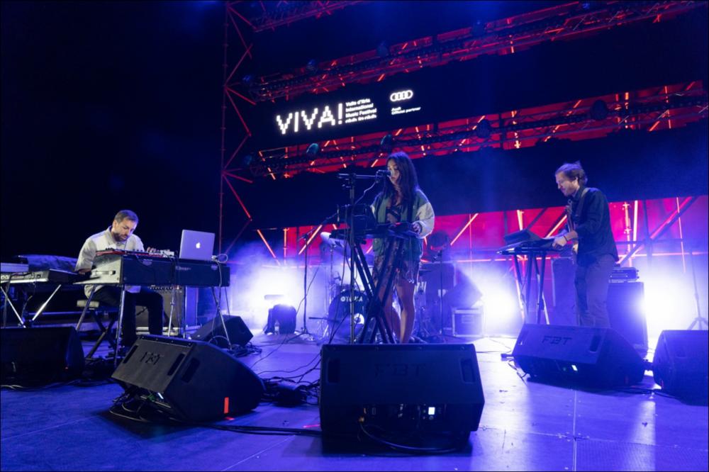 La foto riprende la performance di LNDFK durante la serata di VIVA! Festival 2021 del 6 agosto. LNDFK è una producer e songwriter cresciuta a Napoli, figlia di madre italiana e padre arabo. La sua musica sperimenta l'influenza delle culture diverse che hanno caratterizzato la sua vita e il suo percorso artistico, presentando una commistione di jazz, neo-soul e hip-hop. È apprezzata da numerose radio internazionali (BBC, Worldwide FM, NTS) e ha raggiunto più di un milione di ascoltatori sulle piattaforme digitali. ...