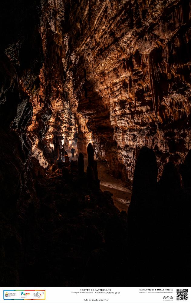 Un lunghissimo e stretto corridoio di roccia dalle tinte rossastre e brune, stalattiti che pendono affilate dal soffitto e dalle bitorzolute pareti, numerose formazioni calcaree si elevano dal basso rendendo difficoltoso il cammino in questo regno sconosciuto, quasi spaventoso.
Siamo all’interno delle Grotte di Castellana, che si sviluppano sotto terra per ben 3.348 metri dando vita ad ambienti colmi di fascino naturale: grotte, anfratti, gallerie, cunicoli, nicchie.
L’immagine digitale fa parte della raccolta di fotografie prodotte da Carlos Solito per il Progetto digitale “Sillabario sotterraneo – Viaggio dantesco nelle Grotte di Puglia” – realizzato nell’ambito della LEGGE REGIONALE 30 dicembre 2020, n. 35 - art. 39 “Cavità pugliesi e opera dantesca - Celebrazioni 70...