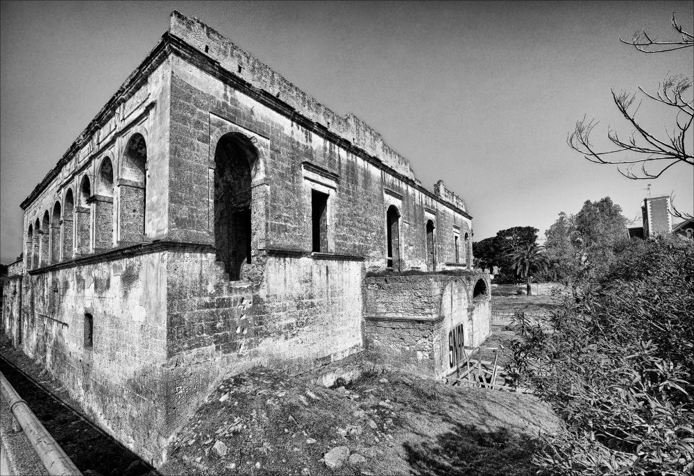 La fotografia è parte di una più ampia raccolta di fotografie realizzate per il progetto di censimento di 248 masserie pugliesi avviato da Giancarlo Chielli, professore del corso in Beni Culturali e Ambientali presso l'Accademia di Belle Arti di Bari. Il lavoro svolto ha dato vita al volume “Le masserie di Puglia come Bene Culturale” in cui sono presenti alcuni scatti di masserie pugliesi tra cui quella in oggetto. Situata in pieno contesto urbano, sul cavalcavia che unisce Viale Papa Giovanni XIII e Viale Pasteur a Bari dove un tempo si trovava la lama Lamberti, la masseria si presenta in evidente stato di abbandono. È una possente architettura rettangolare, a blocco compatto su due livelli distinti da un marcapiano, tipica del Settecento, un tempo posseduta dalla fami...