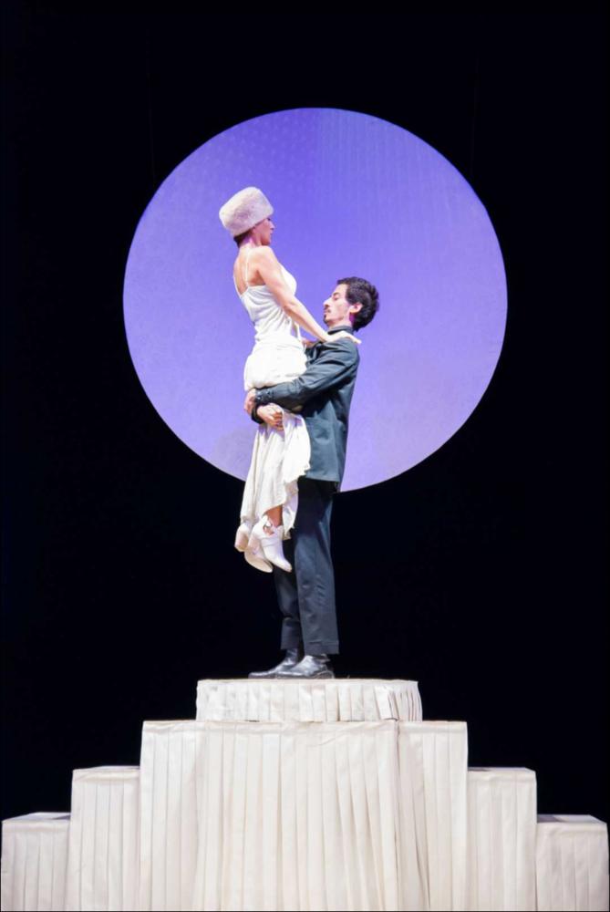 L'immagine in oggetto, fotografia digitale ad opera di Angela Chezzi, cattura un momento dello spettacolo “Il Matrimonio”, per la regia di Salvatore Tramacere, tratto dall'opera teatrale del 1842 di Nikolaj Vasil'evič Gogol', satira incentrata su una giovane donna, Agafija, corteggiata da quattro scapoli, ognuno con le sue eccentricità. Gli stessi personaggi vengono catapultati da Tramacere nel nostro tempo, portando con sé i lati più buffi e divertenti. Il palcoscenico ricorda un set di una trasmissione televisiva, con un presentatore che guida uomini e donne nella ricerca del partner, ma tutto risulta finto e lo schermo allontana ancor più i protagonisti, lasciandoli soli con le proprie inquietudini, aumentando così la distanza tra l'essere e l'apparire. Per far sposa...