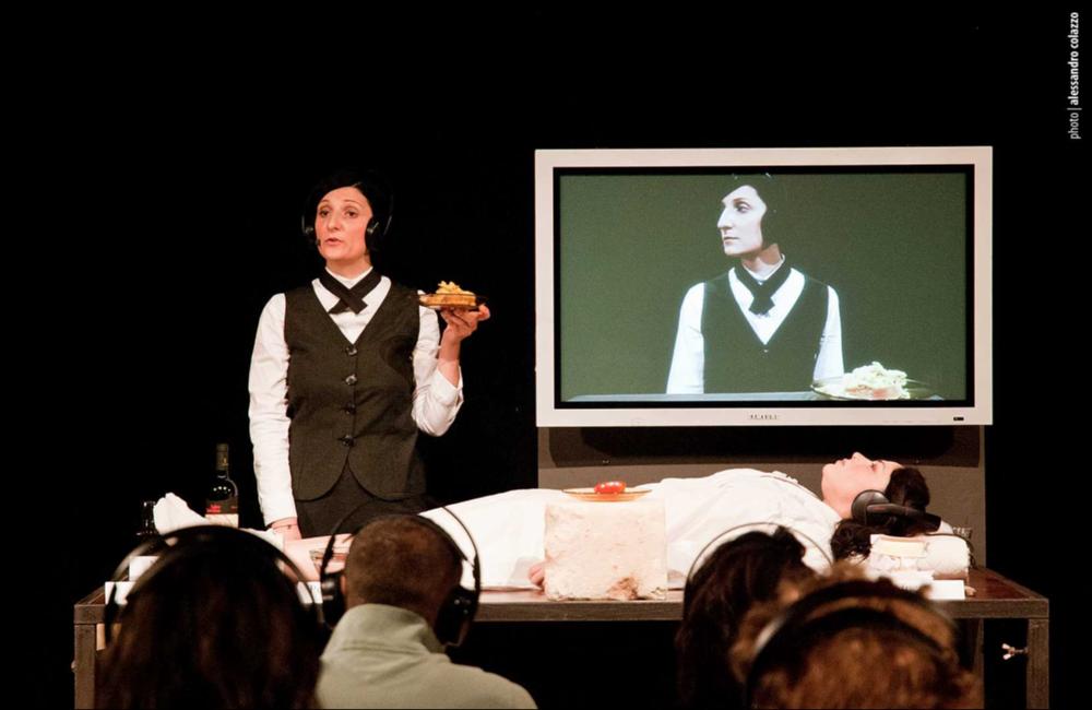 L'immagine in oggetto, fotografia digitale ad opera di Alessandro Colazzo, cattura un momento di “Il pasto della Tarantola”, spettacolo dei Cantieri Teatrali Koreja di Lecce, che fa parte della loro produzione originale e annuale. Con un format originalissimo e all'avanguardia, la rappresentazione teatrale interpretata, da Ottavia Perrone e Maria Rosaria Ponzetta, punta a coinvolgere lo spettatore nella scoperta dei sapori tipici salentini. Mùscari, scapèce, pomodori secchi sott'olio, africani e il vino negramaro ornano una tavola dove una delle attrici è distesa silenziosamente, mentre l'altra comincia il racconto dei prodotti tipici e guida il pubblico in una degustazione individuale. Il Salento emerge in tutta la sua forza e fascino, anche nel racconto di un fenomeno...