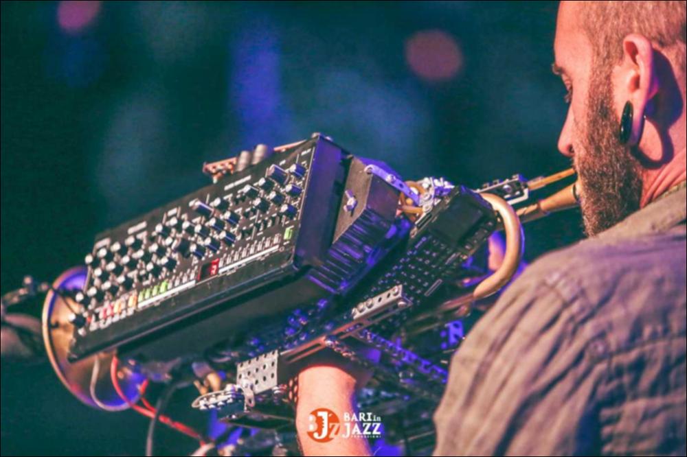 "Bari in Jazz" è un Festival Metropolitano con cadenza annuale, organizzato da Abusuan in Puglia, presenta concerti con ospiti nazionali ed internazionali. L’edizione 2018 del Festival Metropolitano "Bari in Jazz", la quattordicesima, è stata interamente dedicata alle figure femminili nella musica e nel jazz, nel canto, nella composizione e nell’arrangiamento, nell’uso dei vari strumenti e stili musicali. Come ogni anno il Festival Metropolitano Bari in Jazz, luogo d’incontro della musica jazz con altri generi musicali, offre una vetrina d’eccellenza alle grandi artiste e a quelle emergenti, promuovendo anche nuove creazioni. La fotografia mostra l'artista Giorgio Distante mentre suona uno strumento originale, una tromba autocostruita che è una sintesi tra elettronica e...