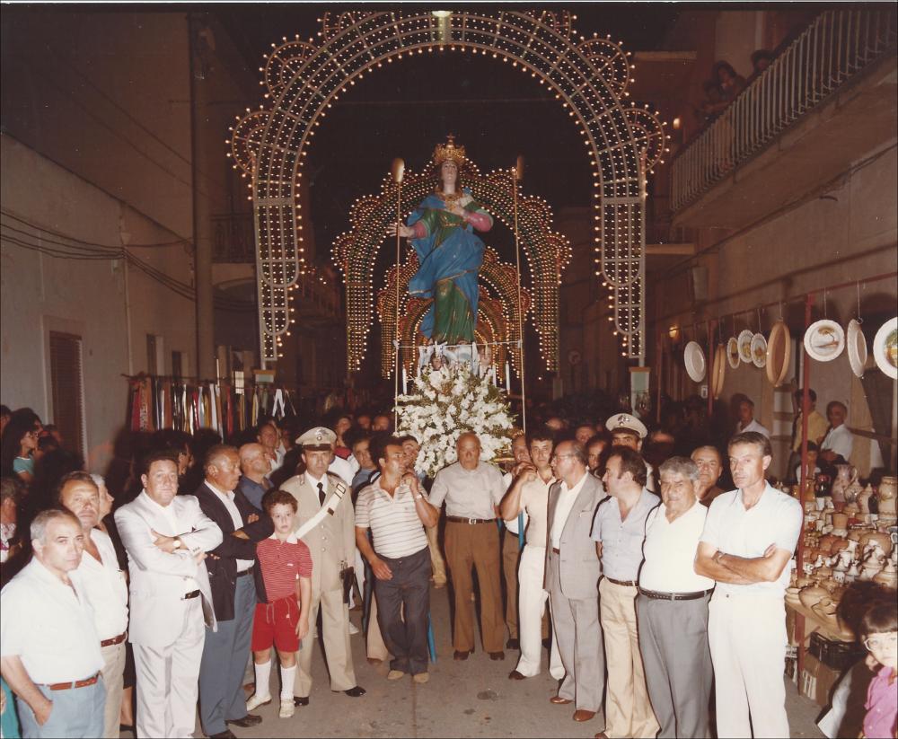 <div class="ql-editor"><div>L'immagine digitalizzata degli anni '90 è testimonianza della profonda devozione popolare per la Santa Patrona di Alezio: la statua votiva di Santa Maria della Lizza viene portata in Processione, accompagnata da una folla di fedeli.</div><div>Questa Festa rappresenta il momento più solenne e significativo del calendario religioso e civile della comunità di Alezio, piccolo centro del Salento in provincia di Lecce. Si celebra ogni anno il 14, 15 e 16 agosto e si distingue per la profonda devozione popolare, l’intensità delle celebrazioni liturgiche e la ricchezza delle manifestazioni civili e culturali che la accompagnano.</div><div>Fulcro della festa sono i riti religiosi in onore di Santa Maria della Lizza, Patrona d...