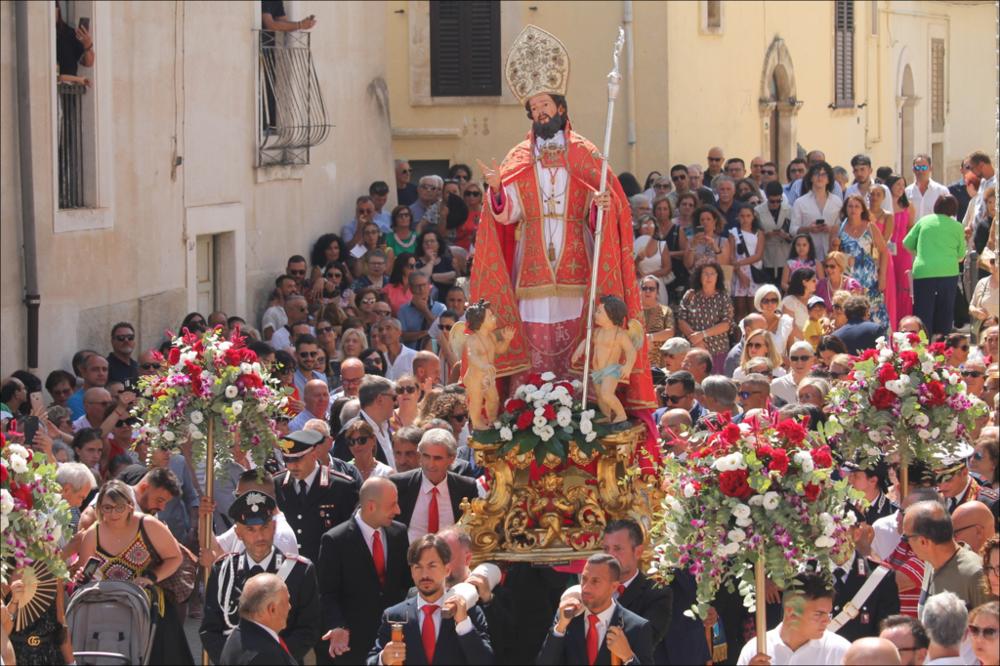 Lo scatto fotografico immortala il momento in cui la Statua di Sant'Oronzo, Patrono di Turi, esce dalla chiesa, accolto da una folla festante di fedeli.
La Festa Patronale di Sant’Oronzo, che si celebra il 25 e 26 agosto, è molto più di una ricorrenza religiosa: è un intreccio di fede, tradizione e spettacolo capace, ogni anno, di coinvolgere l’intera comunità.
Simbolo indiscusso della festa è il maestoso Carro Trionfale: un’imponente torre lignea, trainata da sei mule, che riaccompagna il Santo dalla grotta fino al cuore del paese, tra giochi di luce, musica festosa e una folla gremita di emozione.
Il 25 agosto è dedicato alla Processione alla Grotta. Il busto di Sant’Oronzo parte dalla Chiesa Madre e viene accompagnato in preghiera fino al Santuario di Sant’Oronzo all...