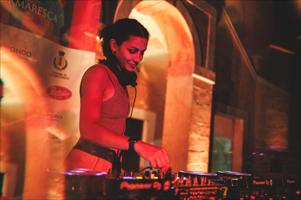 <div>Lo scatto cattura un istante dell’esibizione di <strong>Deena Abdelwahed</strong>, nella serata del 10 agosto 2024 presso la Masseria Ferragnano di Locorotondo per la XX edizione del Locus Festival. Produttrice e DJ tunisina con base in Francia, è oggi una delle voci più innovative della musica araba contemporanea, capace di fondere sonorità tradizionali con una ricca gamma di contaminazioni elettroniche e dance.</div>...