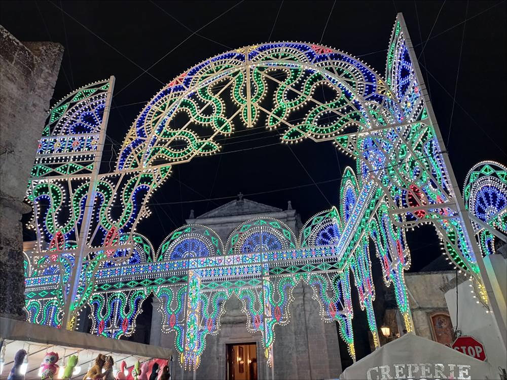 <div class="ql-editor"><div>Lo scatto fotografico presenta il suggestivo allestimento della piazza di Andrano (LE) con luminarie multicolori, in occasione della Festa Patronale della Madonna delle Grazie.</div><div>Questa festa patronale affonda le sue radici nell’antico culto mariano promosso dai monaci basiliani tra l’VIII e il X secolo nell’area dell’Attarico, dove ancora oggi una suggestiva grotta rupestre testimonia la loro presenza e la profonda spiritualità che caratterizzò quel periodo.</div><div>A seguito di un evento miracoloso avvenuto il 17 ottobre 1819, la comunità di Andrano chiese e ottenne da Papa Pio VII il riconoscimento del Patrocinio della Vergine sotto il titolo delle Grazie. Successivamente, nel 1835, Papa Gre...