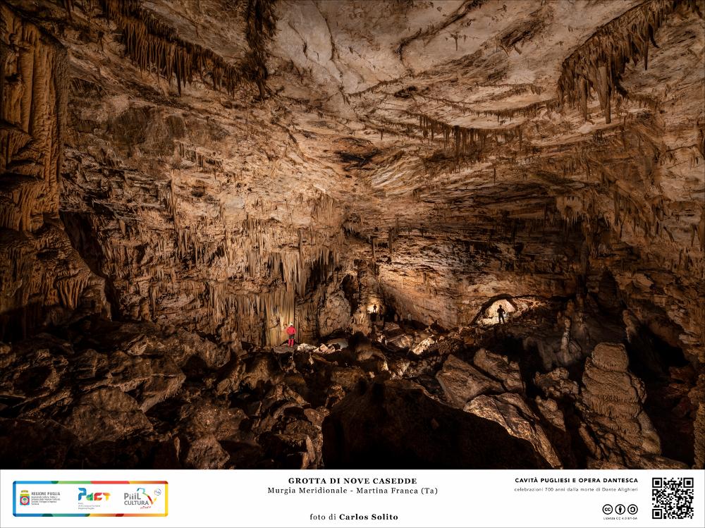 Siamo nella Grotta di Nove Casedde, a Martina Franca. Una tra le più grandi caverne nel sottosuolo delle Murge meridionali, frequentata dal terzo millennio a.C. fino all’Alto Medioevo.
Molto probabilmente questa caverna più che una dimora fu un luogo di culto, come testimoniano le incisioni e i preziosi graffiti venuti alla luce già intorno alla metà del Novecento.
La vastità di questo ambiente è sorprendente, da lasciare senza fiato e far pensare a un mondo infernale, popolato da miserabili dannati: il soffitto di roccia è altissimo e quasi disorienta, ammassi di enormi detriti dalle forme più strane si alternano a concrezioni stalagmitiche altrettanto imponenti, le fiancate irregolari della caverna sono straripanti di piccole e affilate stalattiti che scendono giù com...