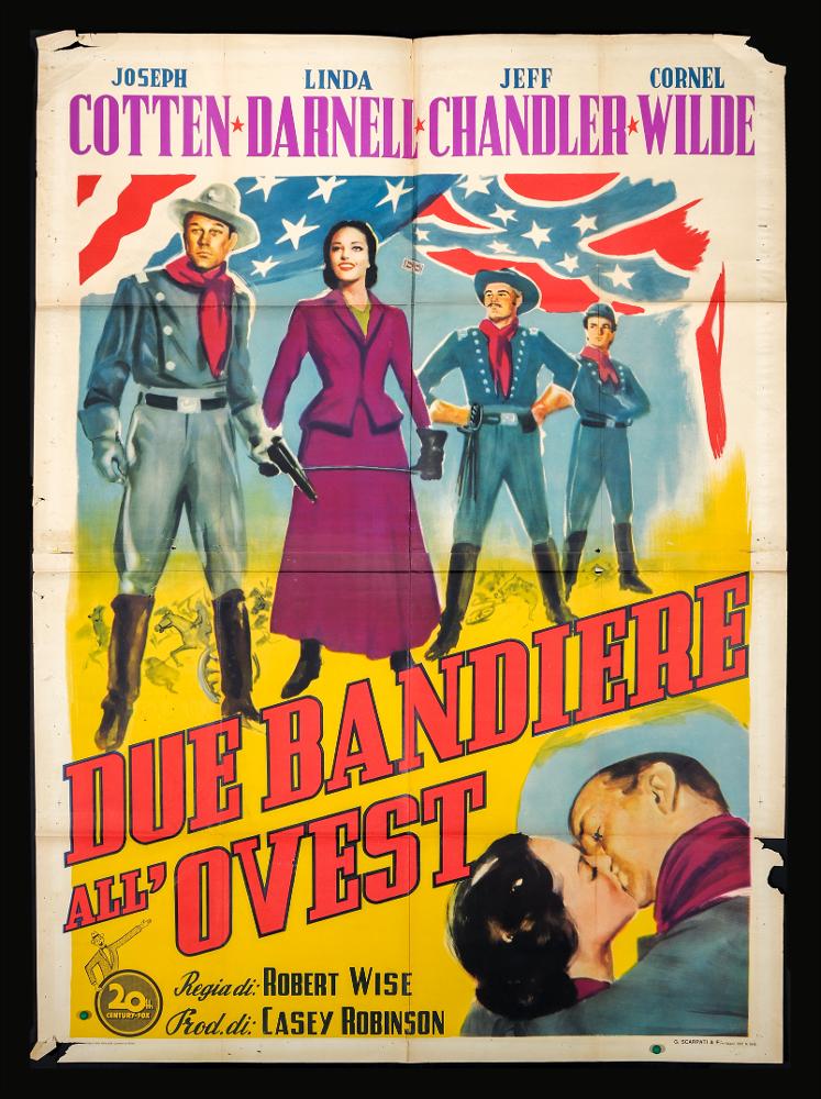 L'immagine riproduce uno dei manifesti conservati presso la Mediateca Regionale Pugliese (vedi Note). Si tratta della versione grafica del manifesto del film "Due bandiere all'Ovest". Senza firma, la composizione si presenta vivace nei colori e descrittiva, mostrando evidenti richiami all'ambientazione western e americana, soprattutto con la presenza dei colori e delle forme tipiche della bandiera. Lo spazio è idealmente diviso in due dal titolo con un lettering chiaro e decorativo, che lo taglia in diagonale creando più momenti narrativi....