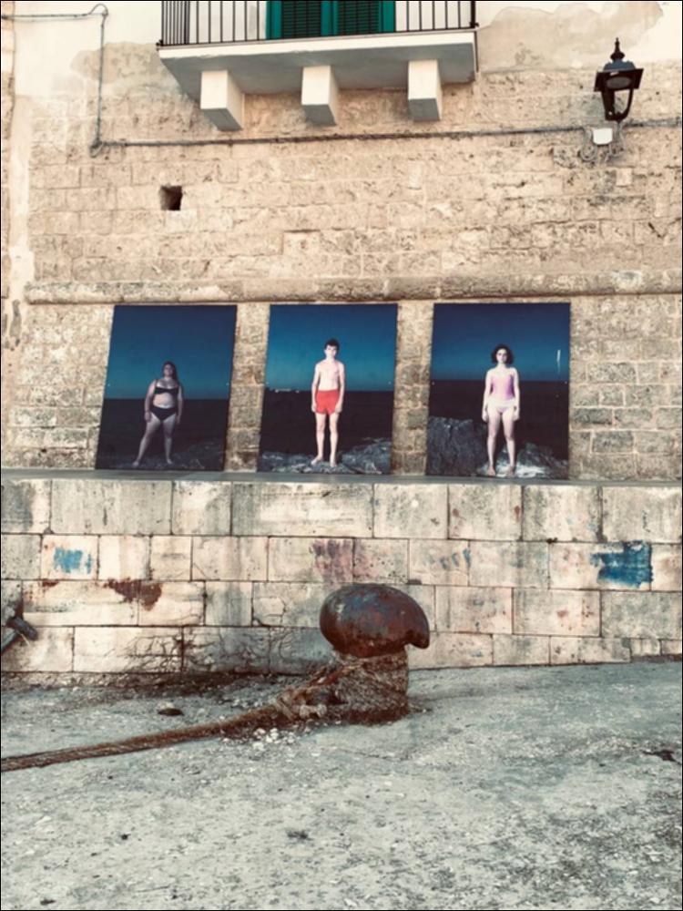 La mostra fotografica è stata allestita lungo le mura del Porto Vecchio di Monopoli. Le fotografie, realizzate durante la settimana del festival, ritraggono adolescenti, anche ragazzi locali, che frequentano la zona vicino allo skate park di Porta Vecchia. I giovani sono stati ritratti con il mare sullo sfondo, ma senza localizzare lo scatto, ossia creando un effetto che trascende il luogo e lo spazio. Gli scatti rispondono ad una necessità di essere semplicemente ‘individui’, senza pregiudizi e omologazione, come invece viene suggerito da una società consumistica e brandizzata. La dimensione reale delle stampe aumenta il coinvolgimento dell’osservatore che si muove in questa “folla” di ragazzi....
