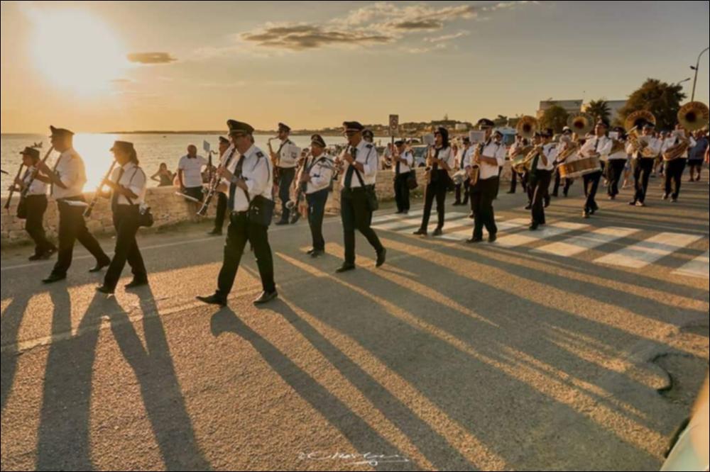 <div class="ql-editor"><div><span>L’immagine digitale raffigura la Banda Musicale di Crispiano, insieme ai suoi musicanti, durante la partecipazione alla Festa d’Estate, svoltasi nel 2019 sul lungomare di Pulsano (TA).</span></div><div>La Banda Municipale “Città di Crispiano”, in provincia di Taranto, nasce nel 1997 come sezione musicale della Biblioteca Civica “Carlo Natale” e si costituisce formalmente come Associazione Musicale nel 2000. Da allora rappresenta una realtà culturale, educativa e sociale di rilievo per il territorio.</div><div>L’associazione promuove la tradizione bandistica e la formazione musicale attraverso una scuola diretta dal prof. Bolognino, che offre percorsi di orientamento, formazione strumen...