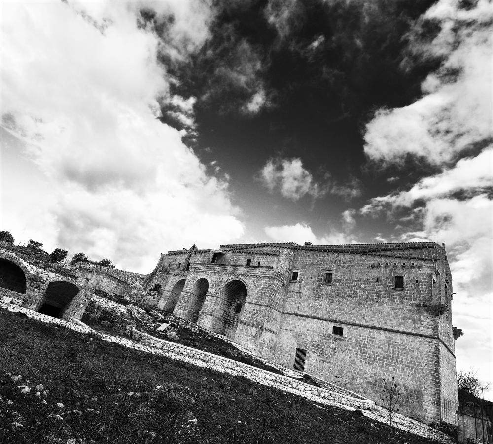 L'istantanea fa parte di una più ampia raccolta di fotografie digitali realizzate per il progetto di censimento di 248 masserie pugliesi avviato da Giancarlo Chielli, professore del corso in Beni Culturali e Ambientali presso l'Accademia di Belle Arti di Bari. Il lavoro svolto ha dato vita al volume “Le masserie di Puglia come Bene Culturale” in cui sono presenti alcuni scatti di masserie pugliesi tra cui quella in oggetto. L'immagine è una inquadratura grandangolare, generata in bianco e nero e post prodotta per evidenziare il gioco di contrasti del cielo con le nuvole e accentuare i dettagli delle mura possenti che spiccano sul territorio brullo e desolato. L'opera fotografica è una veduta di Masseria Jesce, antica struttura fortificata, tipica in Puglia; si trova nel...