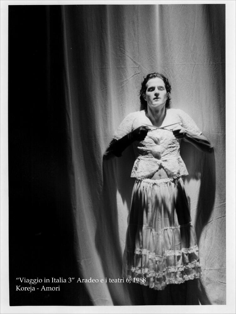La fotografia in bianco e nero cattura un momento intenso della rappresentazione teatrale “Amori”, messa in scena nel 1988 dal Teatro Koreja, nell'ambito della rassegna annuale “Aradeo e i Teatri”, un appuntamento con il teatro sperimentale che la compagnia nata nel 1983 nel piccolo borgo salentino di Aradeo porta avanti sin dall'anno della sua fondazione. “Amori” trae ispirazione dal dramma “Le tre sorelle” di Anton Checov del 1900, immerso nei vizi e nelle dinamiche spesso soffocanti della realtà meridionale. Accomunate dallo stesso destino di vivere insieme, nella stessa casa, in un paese dove non succede niente, le tre sorelle Caterina, Maria e Teresa non possono far altro che raccontare al loro amico "del cuore" i loro segreti, le passioni e la loro voglia di evade...