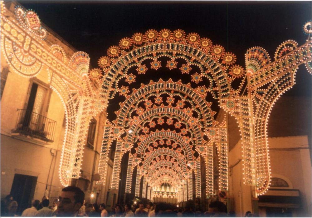 <div class="ql-editor"><div>Lo scatto digitale immortala le suggestive luminarie che abbellirono la cittadina di Sogliano Cavour (LE) nell'anno 1998 in occasione della festa patronale di San Lorenzo Martire.</div><div>La festa dedicata a San Lorenzo Martire si celebra ogni anno il 10 agosto, in memoria del suo martirio. È un appuntamento che la comunità vive con profonda devozione da tempo immemorabile. Accanto al suo intenso significato religioso, la ricorrenza assume anche un importante valore sociale: custodisce tradizioni antiche, rafforza il senso di appartenenza e rinsalda l’identità collettiva. Non è raro, infatti, che molti soglianesi trasferitisi altrove tornino in paese proprio in questa occasione, per ritrovare le proprie radici e co...