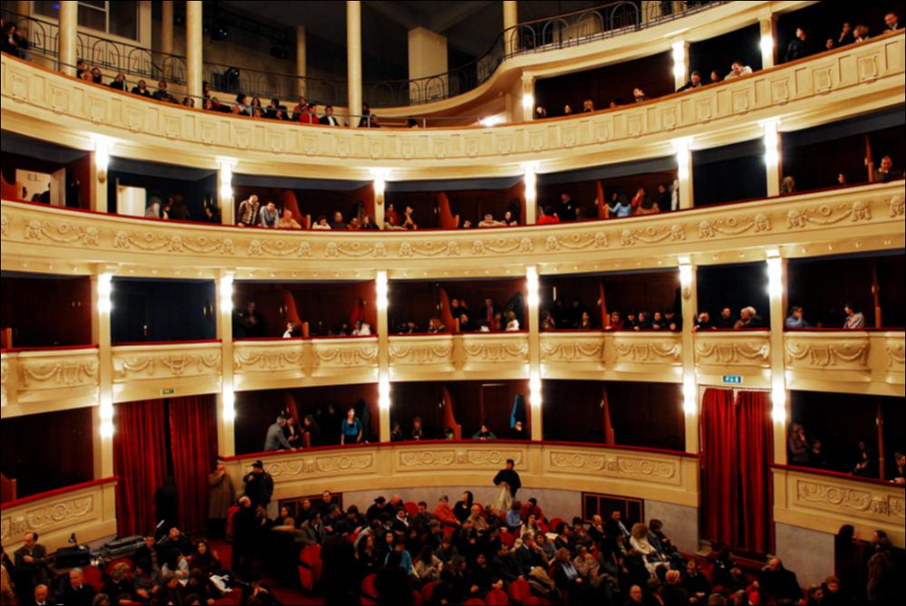 L'immagine è parte della campagna fotografica realizzata dalla fotografa Margherita Mirabella per Teatro Pubblico Pugliese che, con i suoi scatti, ha ripreso le eleganti architetture e i rifiniti dettagli di alcuni dei più bei teatri pugliesi e di alcuni spettacoli teatrali portati in scena in questi ultimi anni. In foto la sala interna del Teatro Comunale "Giuseppe Verdi" di San Severo, riconosciuto come la più grande struttura teatrale di Capitanata e terzo teatro all'italiana più importante di Puglia dopo il Petruzzelli di Bari e il Politeama Greco di Lecce. Il monumento, originariamente denominato teatro Comunale del Littorio, viene progettato dall'architetto Cesare Bazzani rispettando a pieno i canoni stilistici dell'arte fascista. I lavori, iniziati nel 1929, si c...