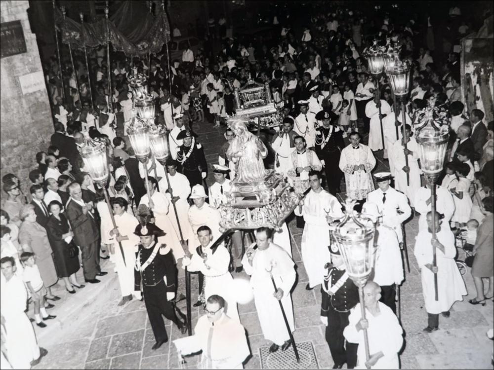 <div class="ql-editor"><div>L’immagine storica, scattata negli anni ‘60, immortala la Processione di gala della Domenica in occasione della festa in onore del Santo Patrono Nicola Pellegrino a Trani.</div><div>I festeggiamenti in onore di San Nicola il Pellegrino, Patrono di Trani, morto in città nel 1094, costituiscono uno degli appuntamenti più importanti della tradizione religiosa e civile tranese.</div><div>La festa patronale si svolge ogni anno nei giorni di sabato, domenica e lunedì della prima settimana di agosto ed è articolata in tre momenti principali.</div><div>Il sabato sera l’effigie lignea del Santo, custodita presso il Santuario di Santa Maria di Colonna, viene trasportata via mare fino al porto di Trani su un’i...