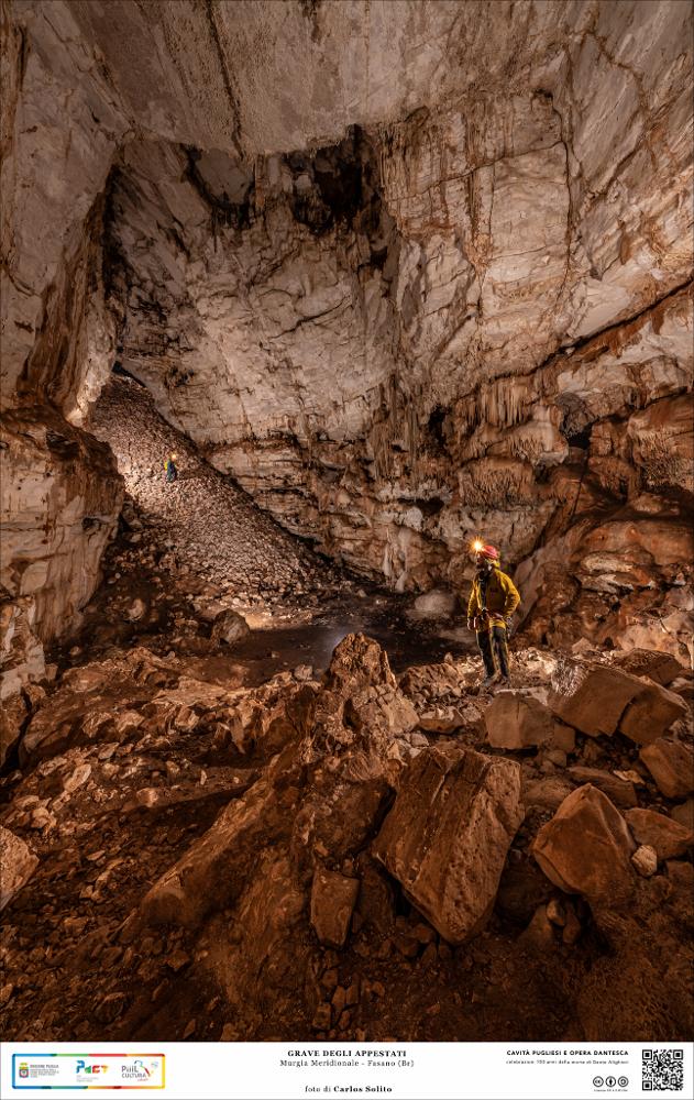 La bella e rigogliosa natura mediterranea nei pressi della Selva di Fasano nasconde nei suoi sotterranei un’enorme cavità, la Grotta degli Appestati, cosiddetta perché era proprio in questa voragine, scavata nelle viscere della terra carsica, che venivano gettati i morti della peste che colpì Fasano alla fine del Seicento.
Protagonista dell’immagine è la caverna rocciosa, traboccante di cumuli di detriti, con le sue pareti possenti, il pavimento fatto di ammassi di macigni giganteschi, il soffitto a strati di pietra massiccia. L’ambiente è freddo, quasi spietato, e non è difficile immaginarlo come dimora eterna per i poveri condannati della pestilenza.
L’immagine digitale fa parte della raccolta di fotografie prodotte da Carlos Solito per il Progetto digitale “Sillabari...