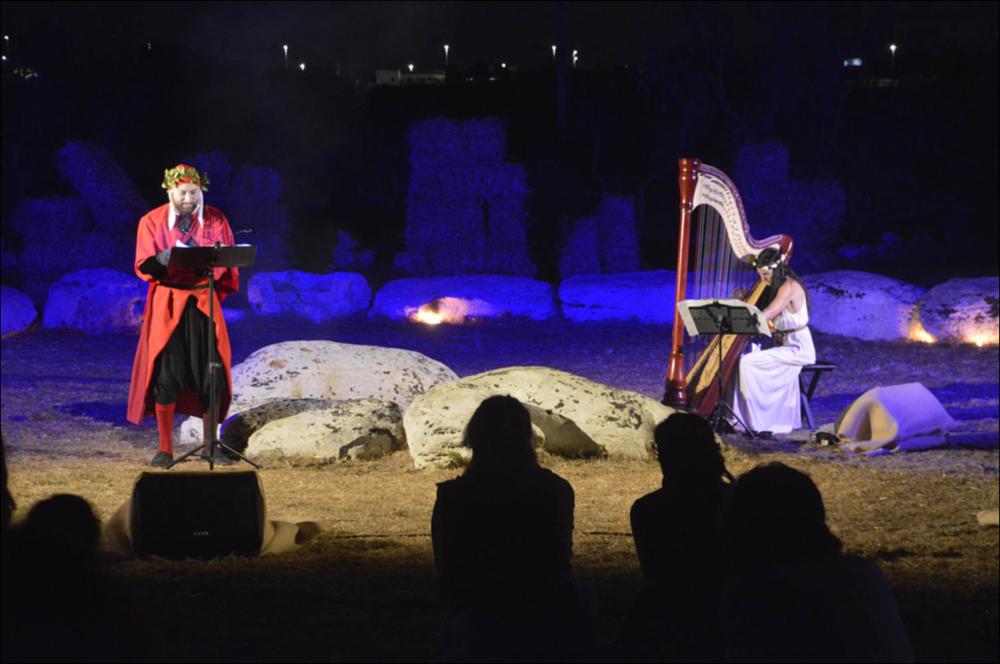 Lo scatto fotografico riprende un momento della performance dell’attore Andrea Sirianni e della musicista d’arpa Angela Cosi, durante la seconda edizione del “Dolmen Festival” 2021. L’attore porta in scena una lettura teatralizzata di alcuni dei più celebri passi dell’Inferno, dalla Divina Commedia di Dante, per celebrare i 700 anni dalla morte del “Sommo” poeta.
La suggestiva location dello spettacolo è località Dolmen “Lì Scusi”, uno dei luoghi simbolo per la storia dell’area di Minervino di Lecce, nota per le sue costruzioni megalitiche tra le più rappresentative della Puglia....