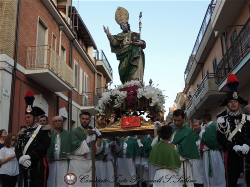 L’immagine fotografica cattura un suggestivo momento della solenne processione della maestosa Statua di San Sabino, Patrono di Torremaggiore, mentre, portata a spalla tra la devozione dei fedeli, attraversa le vie cittadine addobbate a festa. È giugno 2018, e l’intera comunità si raccoglie lungo il percorso per rendere omaggio al suo Santo Protettore, in un’atmosfera intensa di fede, tradizione e partecipazione popolare.
La festa patronale di San Sabino, che si celebra ogni anno a Torremaggiore (provincia di Foggia) nel mese di giugno, rappresenta una delle più antiche e radicate tradizioni locali. San Sabino, vescovo e patrono della comunità, fu proclamato tale nel 1216 attraverso una bolla papale di Onorio III. Sotto la sua protezione, generazioni di torremaggioresi s...
