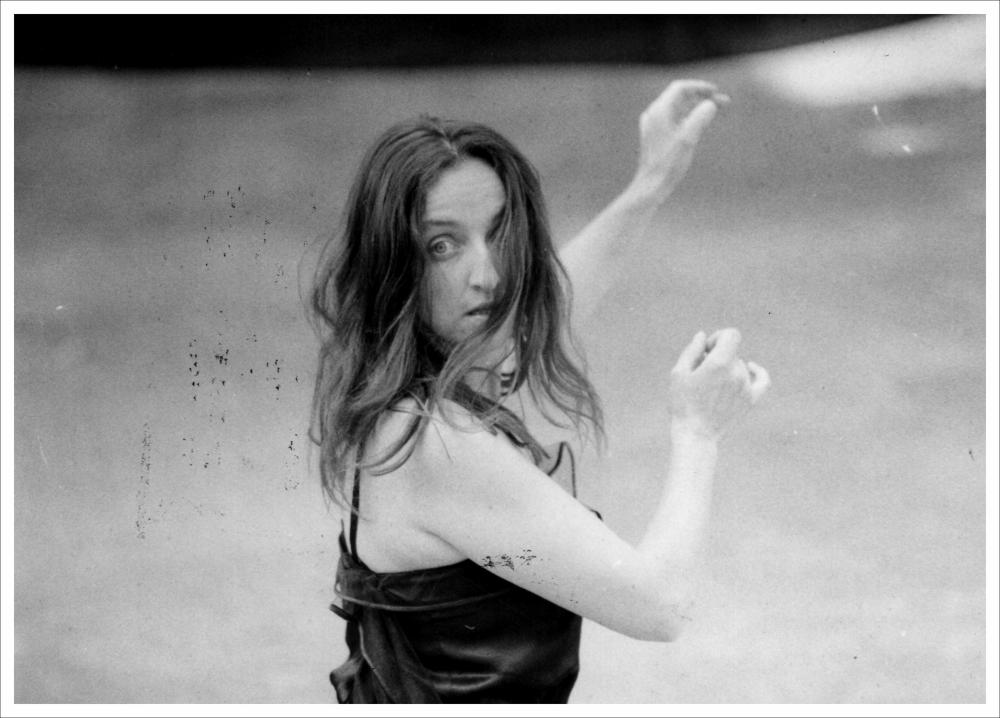 La fotografia in bianco e nero immortala un momento del “concertino” di canti popolari eseguiti da Daniela Piccari e Roberto Licci del Canzoniere Grecanico Salentino, nell'ambito della rassegna annuale “Aradeo e i Teatri” del 1984, alla seconda edizione con il titolo “Concertini”, un appuntamento con il teatro sperimentale che la compagnia nata nel 1983 nel piccolo borgo salentino di Aradeo porta avanti sin dall'anno della sua fondazione. Unico soggetto dell'immagine è Daniela Piccari, attrice formatasi negli anni Ottanta in Danimarca grazie al gruppo “Farfa”, compagnia teatrale che si avvale della collaborazione di attori dalla diversa nazionalità sotto la direzione dell'attrice danese Iben Nagel Rassmussen dell'Odin Teatret. Nel 1985, con l'attrice danese Tove Bornhof...