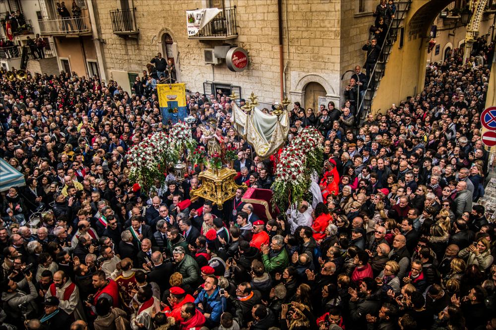 <div class="ql-editor"><div>La foto, ripresa dall’alto, mostra il <strong>simulacro di San Trifone</strong> mentre attraversa la folla durante la processione ad Adelfia. Dall’alto si apprezza il percorso tra le strade affollate di fedeli, con i colori vivaci delle luminarie e la concitazione del momento, catturando l’energia e la devozione che animano la festa patronale. </div><div><br></div><div>La Festa di San Trifone di Adelfia, conosciuta come “La Regina delle Feste”, è tra le celebrazioni patronali più spettacolari della Puglia. Si svolge ogni anno nei primi giorni di novembre e culmina il 10 novembre con la solenne processione del simulacro di San Trifone, preceduta dalla simbolica consegna delle chiavi della città. Pro...