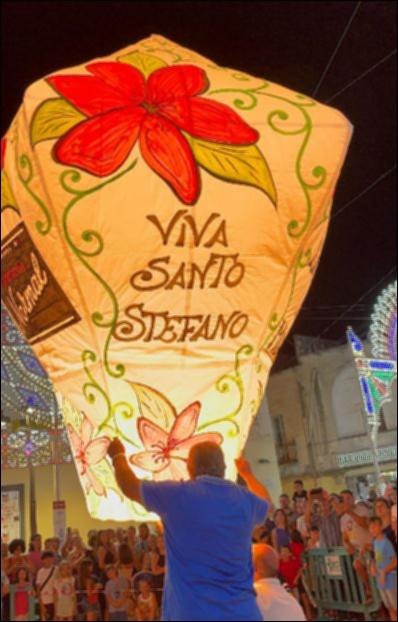 <div class="ql-editor"><div>La fotografia ritrae un uomo mentre sorregge una lanterna devozionale di carta recante la scritta “Viva Santo Stefano”, davanti al pubblico della Festa Patronale.</div><div>La "mongolfiera" di carta, spesso recante scritte o simboli del Santo protettore, è un elemento tradizionale delle feste patronali. Sorreggerla o lanciarla rappresenta un gesto di devozione e partecipazione collettiva, simbolo di preghiere e auguri rivolti al cielo, in un momento di spettacolo e condivisione che unisce fede, cultura e memoria storica della comunità.</div><div><br></div><div>La <strong>Festa Patronale di Santo Stefano</strong> si celebra a Taurisano, in provincia di Lecce, nei giorni 2, 3 e 4 agosto. Sebbene non se ne conosca l...