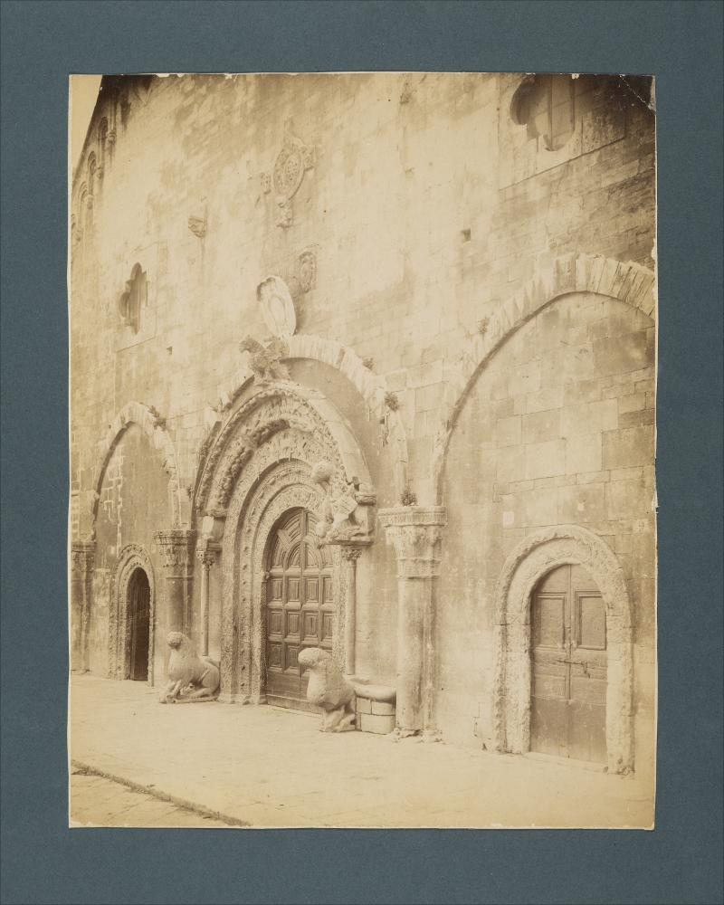 <div class="ql-editor"><div><span>Documentazione fotografica della parte inferiore della facciata e dei portali della Cattedrale di Ruvo di Puglia.</span></div><div><span class="ql-cursor">﻿</span>﻿La raccolta fotografica di Giuseppe Ceci (1863-1938), studioso delle arti figurative dell’Italia meridionale e tra i promotori delle Società di Storia Patria di Napoli e della Puglia, si inserisce nel vivace clima culturale dell’Italia postunitaria, caratterizzato dal progressivo consolidarsi di una «coscienza nazionale» alimentata anche dal confronto e dal dialogo con le realtà storiche e culturali locali.</div><div>Oggi la Biblioteca Comunale di Andria conserva oltre settecento fotografie dedicate alla Puglia medievale, a Napoli...