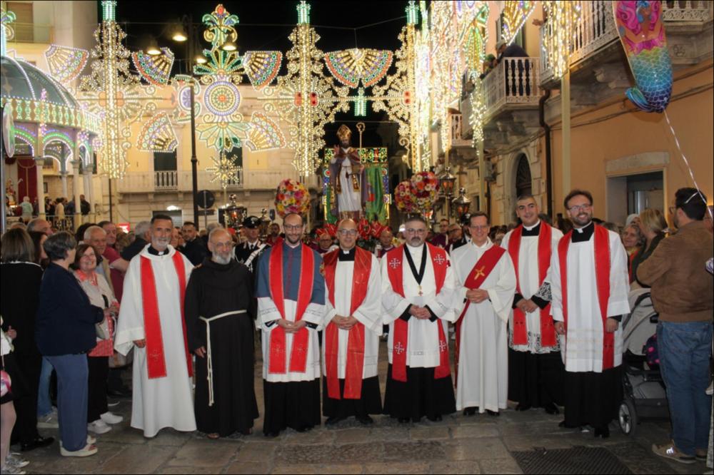 <div class="ql-editor"><div>Questa immagine del 2025 mostra il gruppo dei sacerdoti della Parrocchia di Sant’Erasmo di Santeramo in Colle (BA) pronti per la processione nelle strade cittadine addobbate per la festa in onore del Santo Patrono.</div><div>La Festa Patronale in onore di Sant’Erasmo si celebra il 2 giugno ed è uno degli appuntamenti più sentiti dalla comunità. La giornata è ricca di eventi religiosi e civili che si susseguono nell’arco dell’intera giornata.</div><div>Al mattino si apre con la solenne celebrazione eucaristica presieduta dal Vescovo, alla presenza delle autorità civili e militari e di numerosi fedeli. Segue il tradizionale rito della consegna delle chiavi al Santo Patrono, simbolo di affidamento...