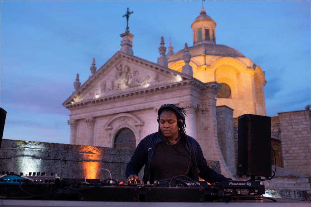 Uno scatto suggestivo riprende l’esibizione della producer e DJ afro-portoghese Nìdia, durante la serata di VIVA! Festival 2021 del 5 agosto. Artista di fama internazionale, con la sua musica in bilico tra avanguardia e nuovo pop, Nìdia porta avanti un’idea di dance alternativa, in particolare nel genere kuduro. Numerose le sue collaborazioni per lo spettacolo The Honey Colony al Southbank Centre di Londra con Bonnie Banane, Kelsey Lu, Lafawndah, Tirzah e Mica Levi. Ha partecipato a festival come Sónar Barcelona, Red Bull Music Festival São Paulo, MoMA PS1 Warm Up, Just Jam al Barbican di Londra, WWWβ di Tokyo. La performance di Nídia è stata trasmessa in streaming worldwide su Boiler Room, piattaforma online londinese, per una partnership ritornata in occasione dell'es...