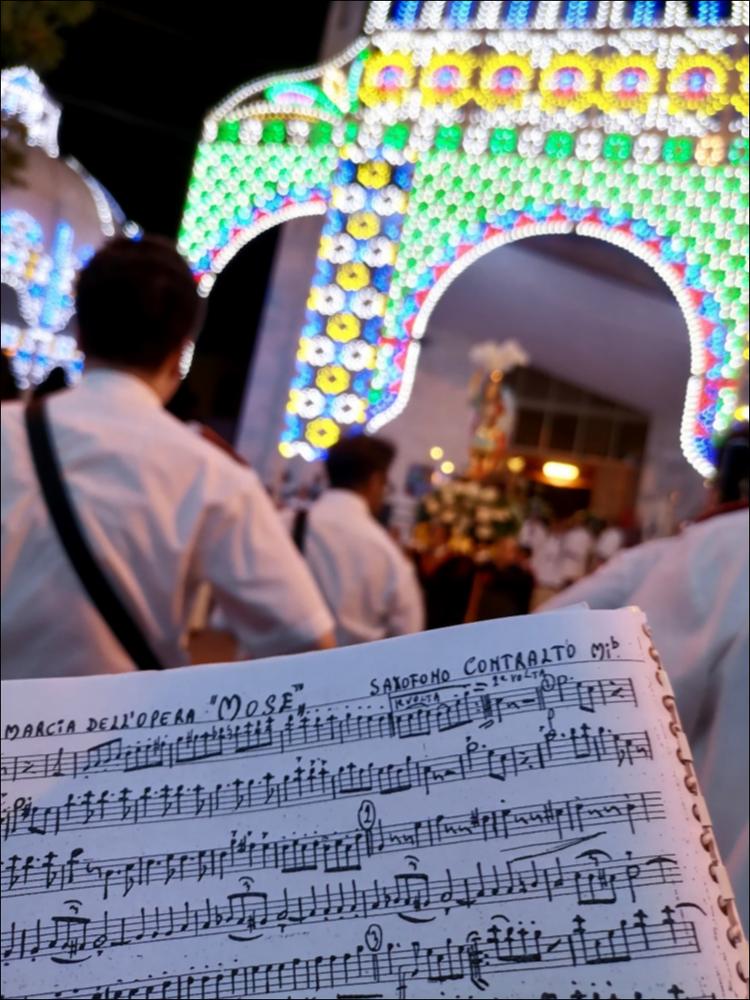 <div class="ql-editor">La fotografia ritrae la banda locale che accompagna l’effige di San Michele Arcangelo lungo le vie di Palese durante la festa patronale del 2022. La musica della banda scandisce il ritmo del corteo, mentre i cittadini seguono la processione tra luminarie e decorazioni, testimoniando la partecipazione viva della comunità e la continuità della tradizione.<div>La Festa Patronale di Palese, borgo a nord di Bari, è dedicata a San Michele Arcangelo, celeste protettore della comunità. Si celebra ogni anno nei primi giorni di agosto e rappresenta il momento più alto e identitario della vita religiosa e sociale del territorio. Le origini della devozione risalgono al 1824, quando l’arcivescovo Clary donò a Palese un...