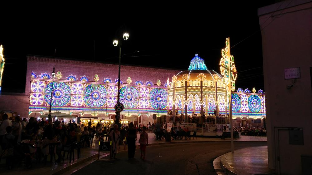 <div class="ql-editor"><div>La fotografia digitale, scatto dell'anno 2013, mostra Piazza San Giovanni allestita con le suggestive luminarie in occasione della festa dei Santi Patroni di Sava, San Giovanni Battista e Maria Santissima di Pasano.</div><div>La Festa si svolge ogni anno nel mese di giugno nel Comune di Sava (TA) ed è uno degli eventi religiosi e popolari più significativi per l’identità storica e culturale della comunità.</div><div>La celebrazione si articola in momenti di forte valore simbolico: la solenne processione delle statue dei Santi Patroni — San Giovanni Battista Bambino e la Madonna di Pasano — accompagnata dalle confraternite, dalle autorità civili, dalla banda musicale e da un’ampia partecipazione...