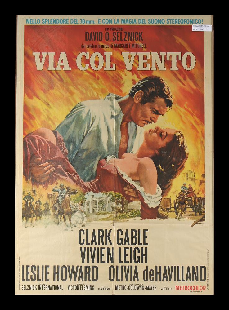 L'immagine riproduce uno dei manifesti conservati presso la Mediateca Regionale Pugliese (vedi Note). Si tratta di una delle versioni grafiche del manifesto del film "Via col vento" colossal del 1939 per la regia di Victor Fleming, adattamento cinematografico dell’omonimo romanzo di Margaret Mitchell del 1936. Il manifesto è a firma di Nano, diminutivo di Silvano Campeggi, illustratore e pittore di fama mondiale, allievo di Luigi Martinati. In questa composizione da un cielo infuocato dalle tinte tra l'arancio e il giallo, sembrano elevarsi i due protagonisti Clark Gable e Vivien Leigh, immortalati in uno dei tanti momenti di grande intensità emotiva, la stratta e lo sguardo di Rhett esprimono tutto il dolore e l'amore per la sensuale Rossella. In basso, in dimensioni n...
